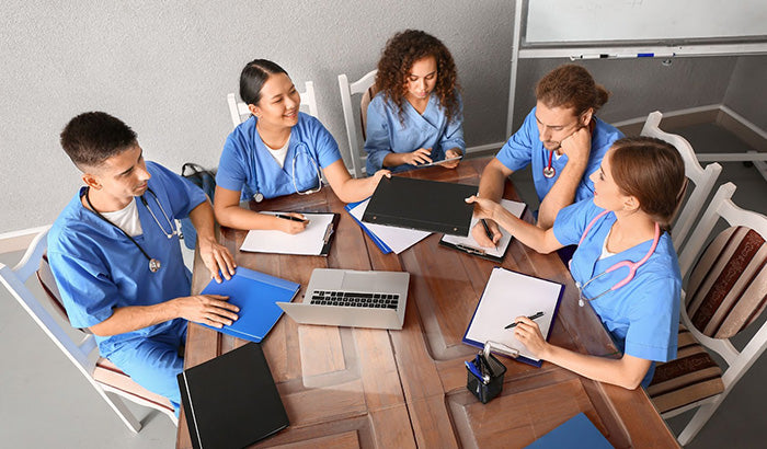 A group of doctors engaged in discussion around a table, emphasizing collaboration in medical education and NCLEX preparation.